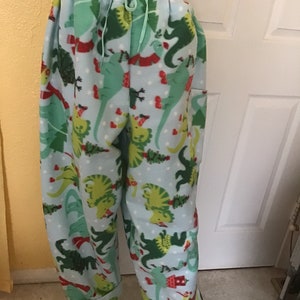 Puede incluir: Pantal&oacute;n de pijama de franela azul con estampado de dinosaurio verde, rojo y blanco. El pantal&oacute;n tiene cintura con cord&oacute;n y piernas con pu&ntilde;os.
