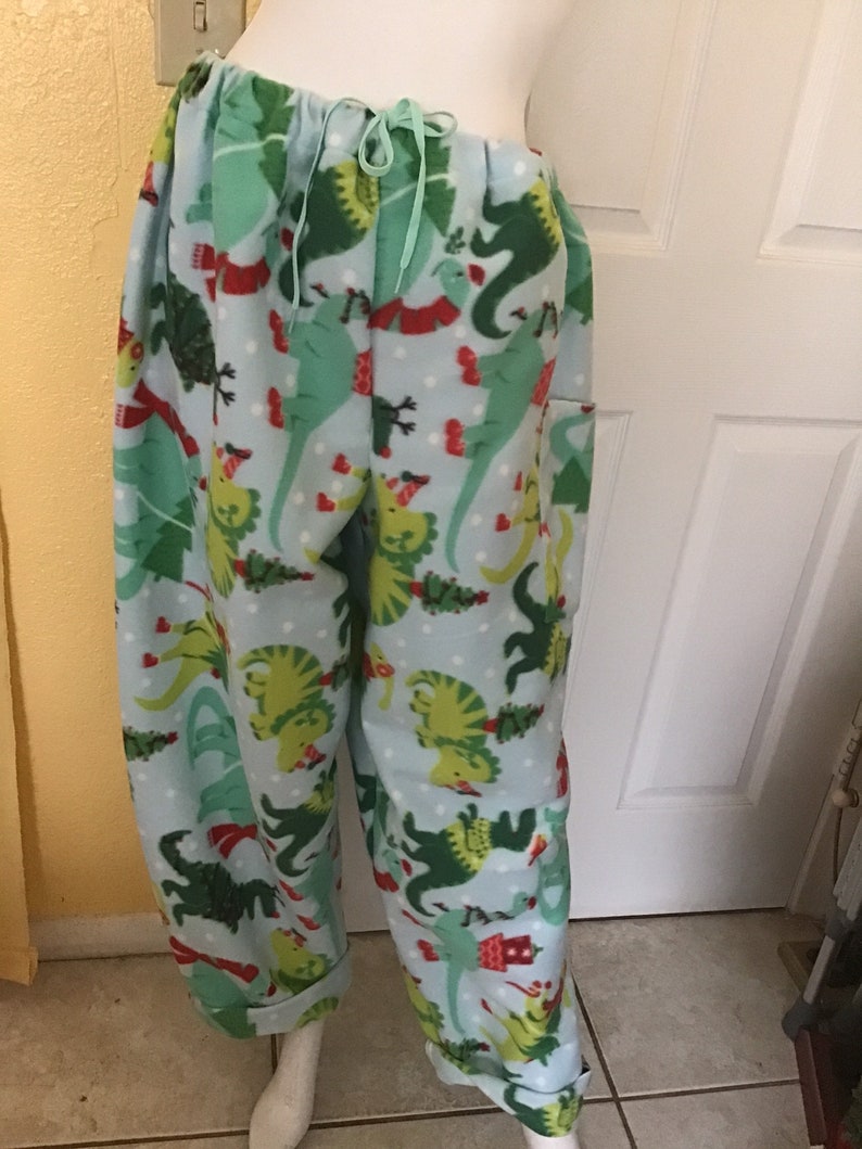 Puede incluir: Pantal&oacute;n de pijama de franela azul con estampado de dinosaurio verde, rojo y blanco. El pantal&oacute;n tiene cintura con cord&oacute;n y piernas con pu&ntilde;os.