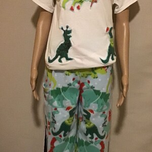 Puede incluir: Camiseta blanca con dise&ntilde;os navide&ntilde;os de dinosaurios verdes. Pantal&oacute;n de pijama azul a juego con dise&ntilde;os navide&ntilde;os de dinosaurios verdes.