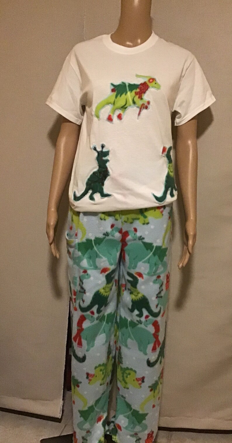 Puede incluir: Camiseta blanca con dise&ntilde;os navide&ntilde;os de dinosaurios verdes. Pantal&oacute;n de pijama azul a juego con dise&ntilde;os navide&ntilde;os de dinosaurios verdes.