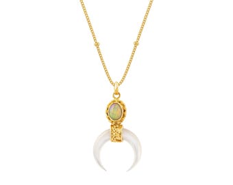 May include: A gold chain necklace featuring a pendant with an oval opal stone set above a white crescent moon-shaped horn. The pendant is connected to a delicate gold link chain, showcasing a polished finish and intricate metal detailing.