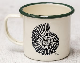 May include: A white enamel mug with a green rim and a black and white illustration of a nautilus shell. The mug has the text "ELINO LORI" printed on the bottom.