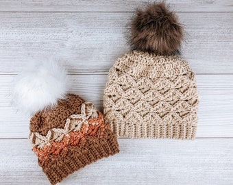 May include: Two crocheted hats with pom poms. One hat is beige with a brown pom pom and the other is brown with a white pom pom. The brown hat has a multi-colored pattern.