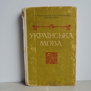 Könnte beinhalten: Ein altes grünes Buch mit dem Titel "Українська мова" in weißen Buchstaben. Das Buch hat ein rotes und goldenes Dekormuster auf dem Einband.