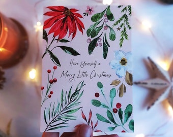 May include: A pink Christmas card with a watercolor design of red poinsettias, green leaves, white flowers, and red berries. The card reads "Have Yourself a Merry Little Christmas".