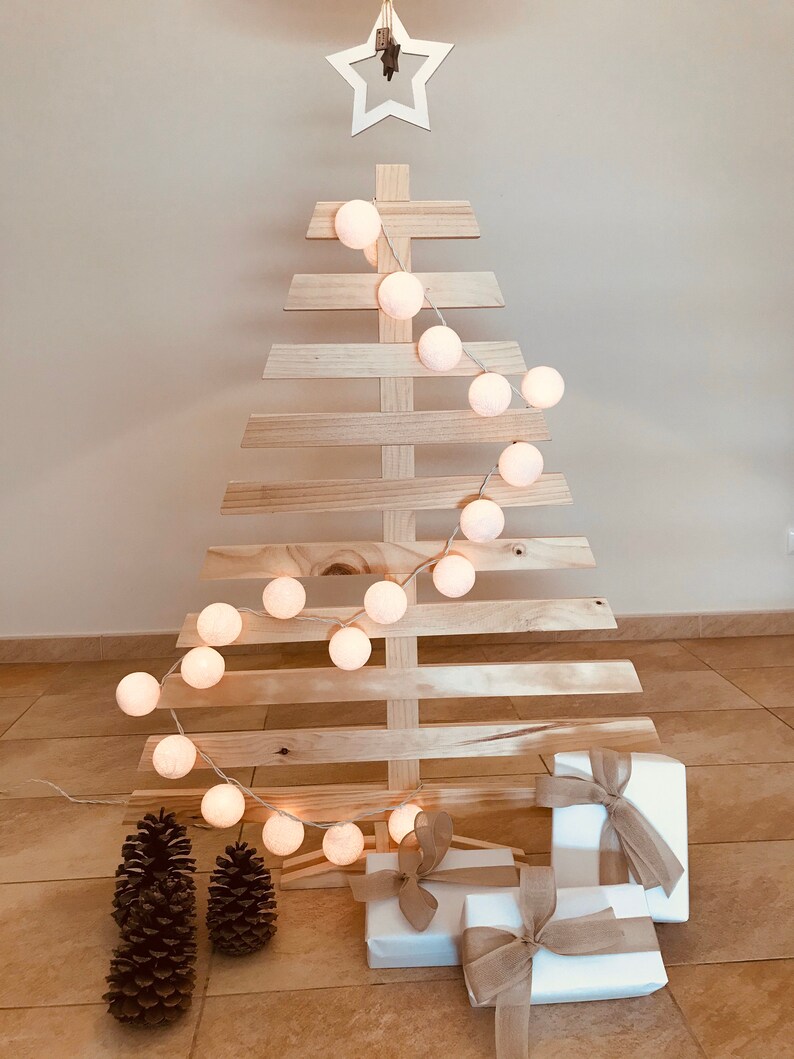 May include: A wooden Christmas tree with white cotton ball lights and wrapped gifts at the base.