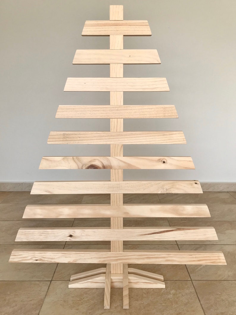 May include: A wooden Christmas tree made of 10 horizontal slats, with a triangular shape and a base with three legs.