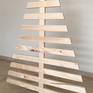 May include: A wooden Christmas tree made of natural wood planks. The tree is freestanding and has a wide base.