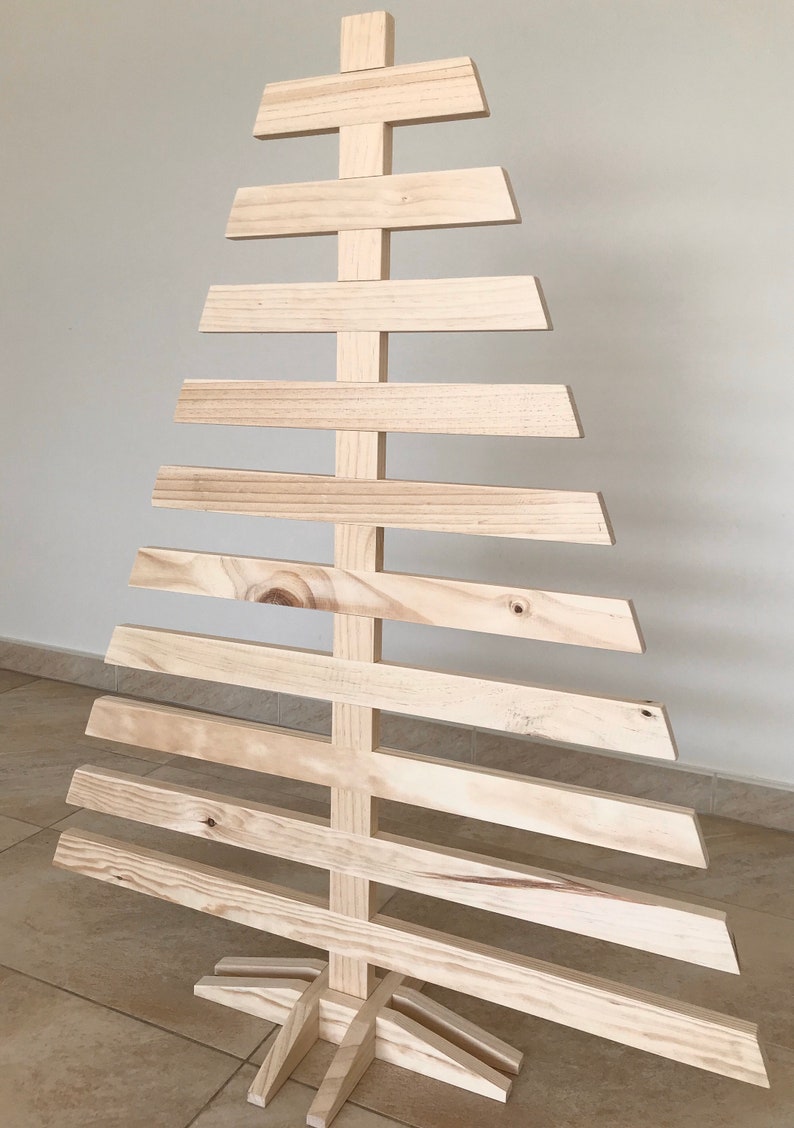 May include: A wooden Christmas tree made of natural wood planks. The tree is freestanding and has a wide base.