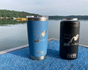 May include: Two YETI stainless steel tumblers with a blue and black finish. Both tumblers feature a lake outline and the text "Life is better on Sylvan".