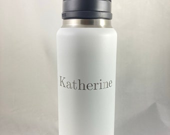 May include: White Yeti water bottle with a black handle and a personalized inscription that reads "Katherine".