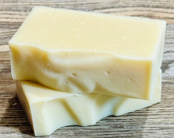 May include: Two bars of white soap stacked on top of each other. The soap is rectangular and has a slightly textured surface.