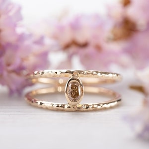 Könnte beinhalten: Ein zarter Goldring mit gehämmerter Oberfläche und einem kleinen ovalen braunen Diamanten, der in der Mitte sitzt.