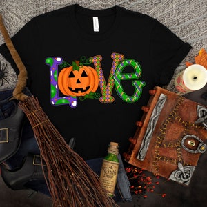 May include: Black t-shirt with a colorful "LOVE" graphic featuring a jack-o'-lantern. The letters are decorated with green, purple, and orange patterns.
