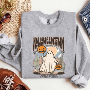 May include: Gray sweatshirt with a graphic print of a ghost holding a jack-o-lantern. The text on the graphic reads "Halloweentown Est. 1998" and "Where being normal is vastly overrated".