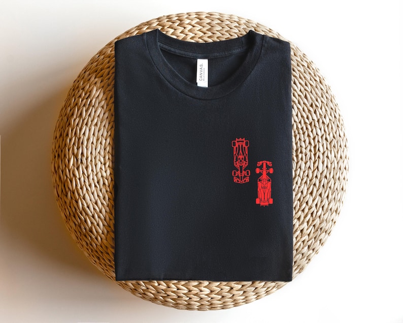 Peut inclure: T-shirt noir avec un contour rouge de deux voitures de course sur le devant.