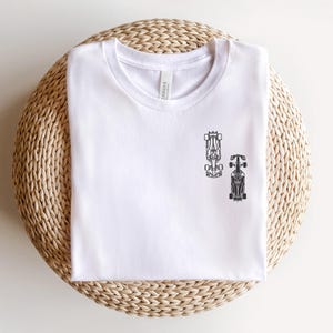 Peut inclure: T-shirt blanc avec un motif noir de deux voitures de course.