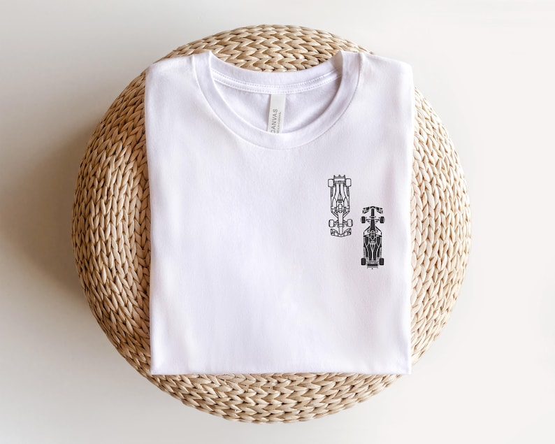 Peut inclure: T-shirt blanc avec un motif noir de deux voitures de course.