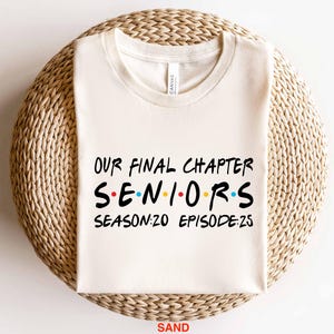 May include: A white t-shirt with the text "Our Final Chapter Seniors Season:20 Episode:25" in black. The word "Seniors" is in a stylized font with colorful dots.