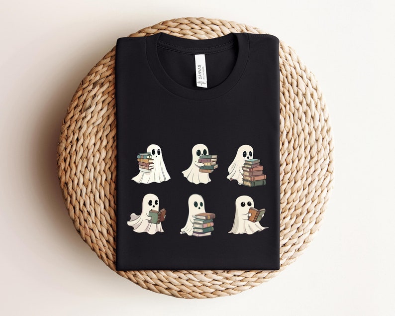 Może przedstawiać: Czarny T-shirt z grafiką sześciu białych duch&oacute;w trzymających lub czytających książki. Duchy są w r&oacute;żnych pozach, niekt&oacute;re trzymają stosy książek, inne czytają jedną książkę.