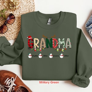 May include: A green Christmas sweatshirt with the word "Grandma" in colorful letters and a snowman design. The names "Sophia", "Alex", "Brandon", and "Olive" are printed below the snowman design.