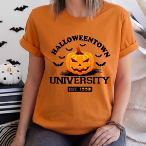 May include: Orange t-shirt with a black graphic of a jack-o'-lantern with the text "Halloweentown University Est. 1998"