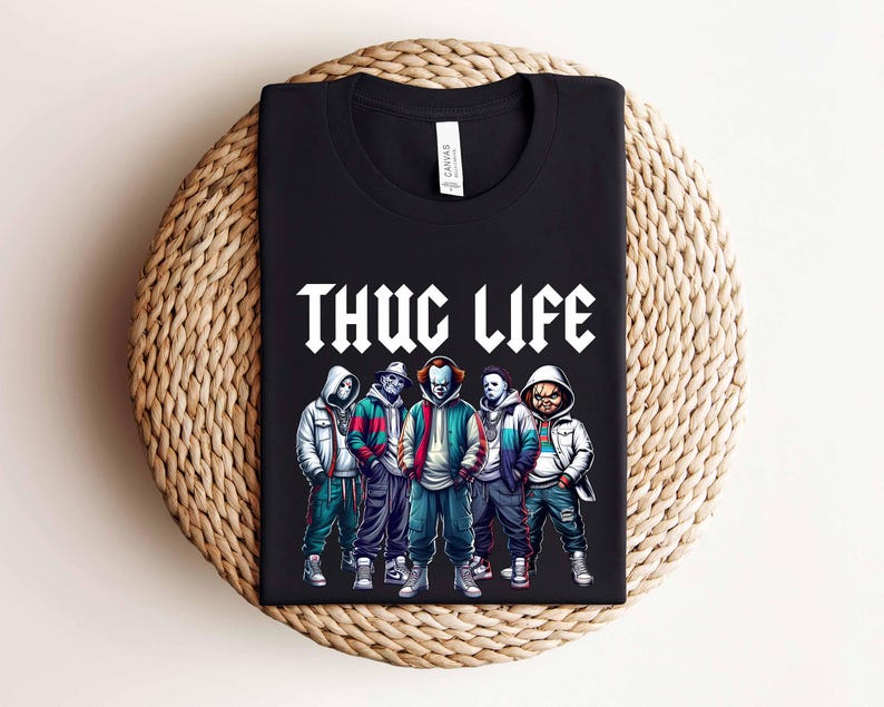 Peut inclure: T-shirt noir avec l'inscription blanche "THUG LIFE", orn&eacute; d'un graphisme de cinq personnages en sweats &agrave; capuche et vestes. Les personnages sont de style cartoon, sur le th&egrave;me de l'horreur.