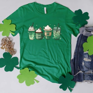 May include: Green t-shirt with a graphic of four coffee cups with shamrocks and the text "Lucky Latte".