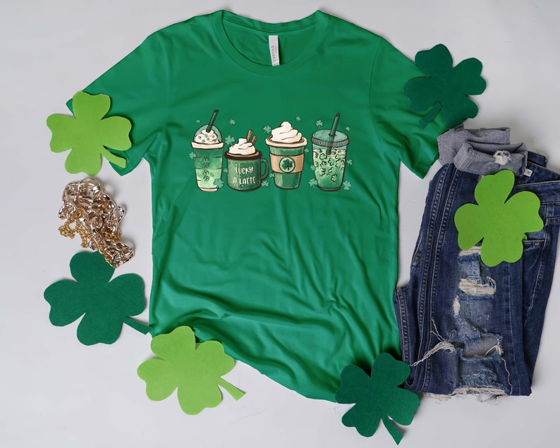 May include: Green t-shirt with a graphic of four coffee cups with shamrocks and the text "Lucky Latte".