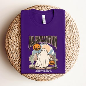 May include: Purple t-shirt with a graphic of a ghost holding a jack-o-lantern. The graphic says "Halloweentown Est. 1998" and "Where being normal is vastly overrated".