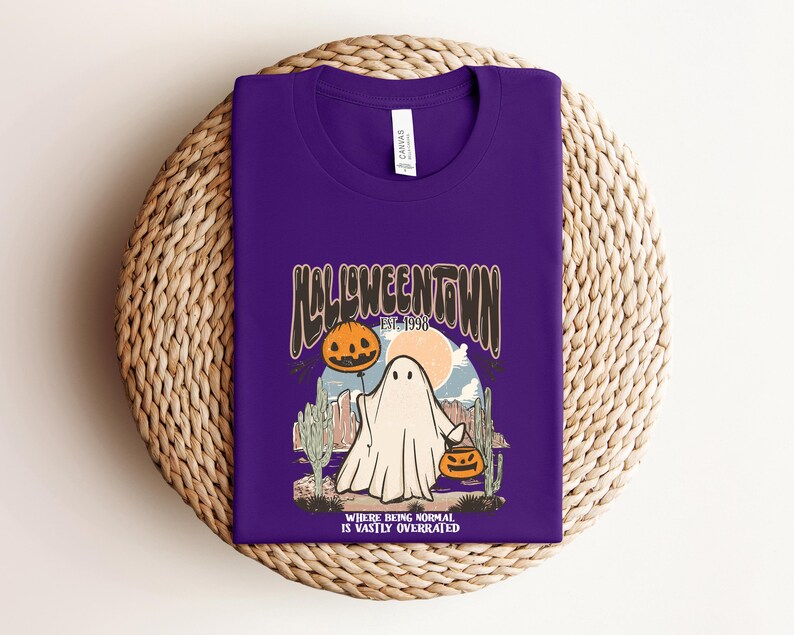 May include: Purple t-shirt with a graphic of a ghost holding a jack-o-lantern. The graphic says "Halloweentown Est. 1998" and "Where being normal is vastly overrated".