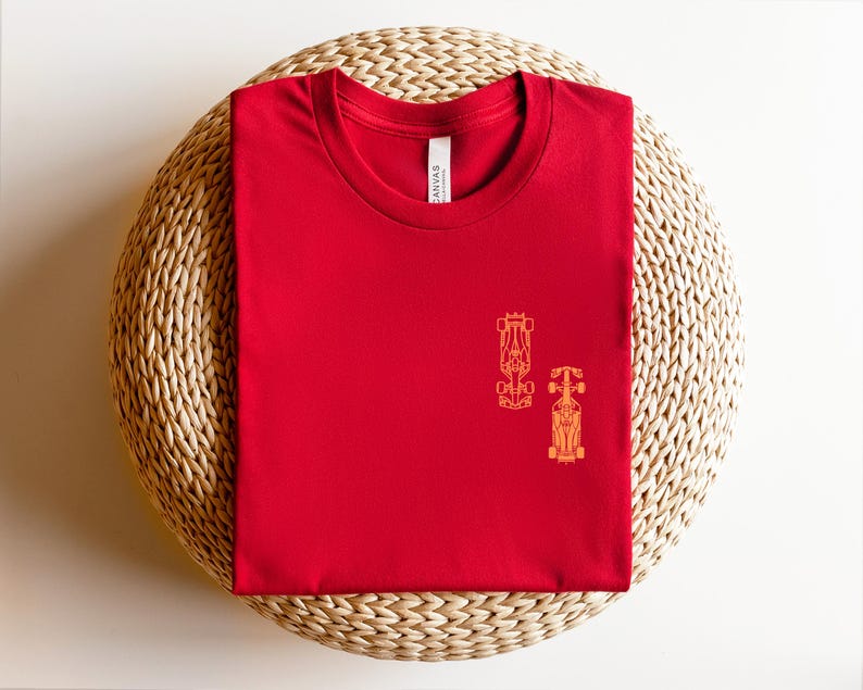 Peut inclure: T-shirt rouge avec un contour jaune de deux voitures de course sur le devant.