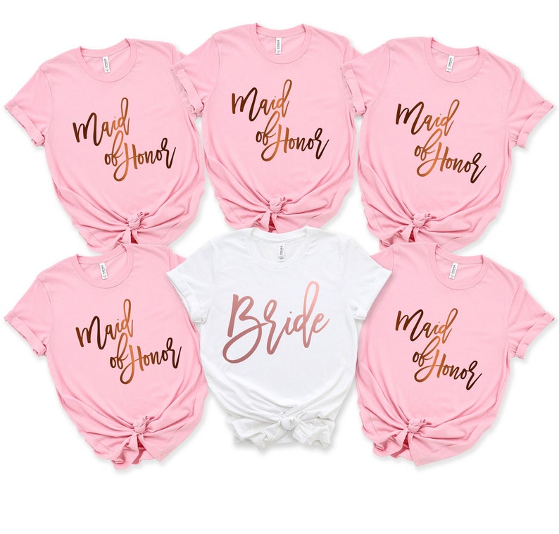 May include: Five t-shirts with rose gold foil lettering. One white t-shirt says "Bride" and four pink t-shirts say "Maid of Honor".