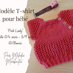 Peut inclure: Un t-shirt rose tricoté pour bébé avec un motif texturé, orné de trois boutons sur le col. Le texte sur l'image indique "Pink Lady" et "Taille 0/4 mois - 5/9 mois - 10/18 mois". Un mètre ruban est visible en arrière-plan.