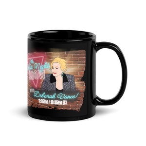 Può includere: Tazza da caffè in ceramica nera con una grafica di una donna davanti a un muro di mattoni con un cartello al neon che recita "The Late Night Show with Deborah Vance! 11:35PM/10:35PM (C)"