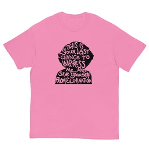 May include: Pink t-shirt with a black silhouette of a person's head and the text "This is your last chance to impress me... and save yourself from elimination."