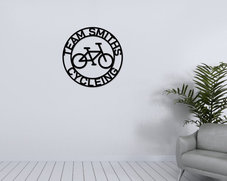 May include: Black metal wall decor with the text "Team Smiths Cycling" in a circle with a bicycle silhouette inside.