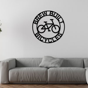 May include: Black metal sign with the text "Brew Built Bicycles" in a circle with a bicycle silhouette inside.