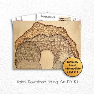 Peut inclure: Un kit de bricolage de string art à télécharger numériquement, présentant un motif géométrique de cercles et d'arches qui se chevauchent. Le motif est réalisé avec de la ficelle brune, beige et grise sur un fond en bois. Le niveau de difficulté est indiqué comme intermédiaire, 3 sur 5.
