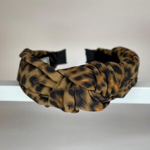 May include: A brown and black leopard print knotted headband.
