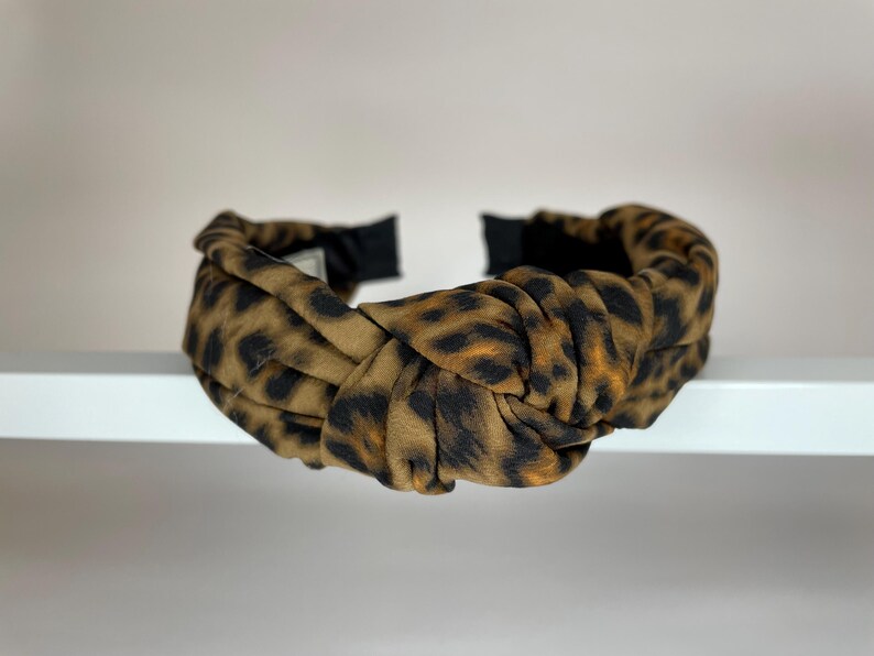 May include: A brown and black leopard print knotted headband.