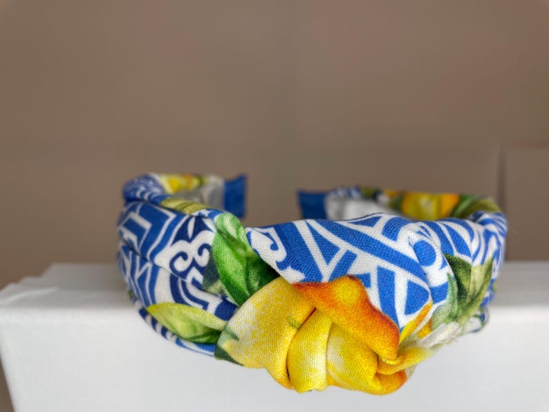 May include: A blue and white headband with a knotted design and a lemon print.