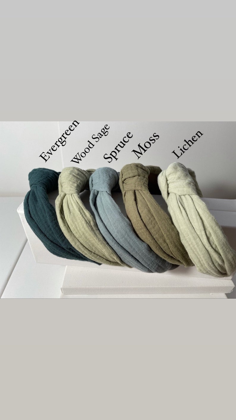 May include: Five knotted headbands in different shades of green. The headbands are labeled "Evergreen", "Wood Sage", "Spruce", "Moss", and "Lichen".