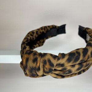 May include: A brown and black leopard print knotted headband.