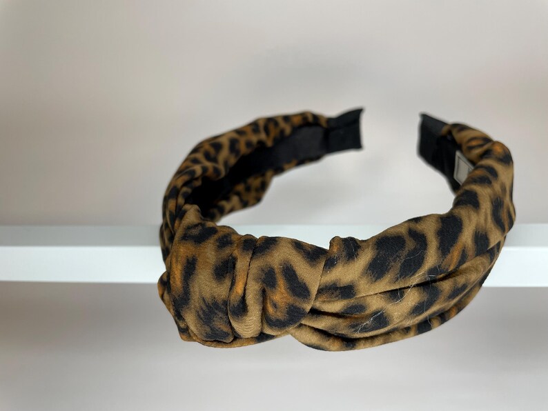May include: A brown and black leopard print knotted headband.