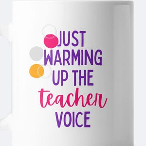 May include: White ceramic mug with a purple, pink, and orange design. The mug reads "Just warming up the teacher voice".