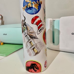 May include: White stainless steel tumbler with a colorful design featuring various Universal Studios attractions, including the globe, the Grinch, the Cat in the Hat, and a dinosaur.