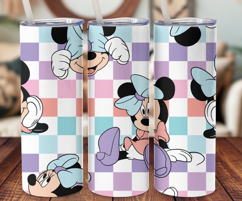 K&ouml;nnte beinhalten: Ein wei&szlig;er Becher mit einem karierten Muster in Rosa, Blau und Lila. Der Becher zeigt ein sich wiederholendes Bild von Minnie Maus in verschiedenen Posen.