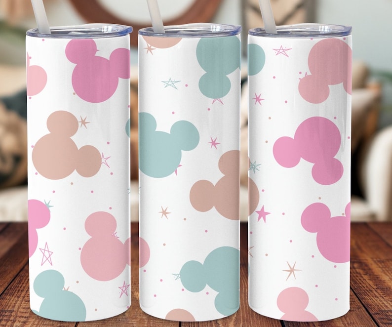 Puede incluir: Tres vasos de acero inoxidable blanco con un patr&oacute;n de cabezas de Mickey Mouse de color rosa pastel, melocot&oacute;n y azul claro y estrellas doradas.