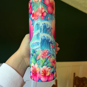 Puede incluir: Un vaso de acero inoxidable con un dise&ntilde;o tropical colorido. El dise&ntilde;o presenta flores rosas, hojas verdes y olas azules.